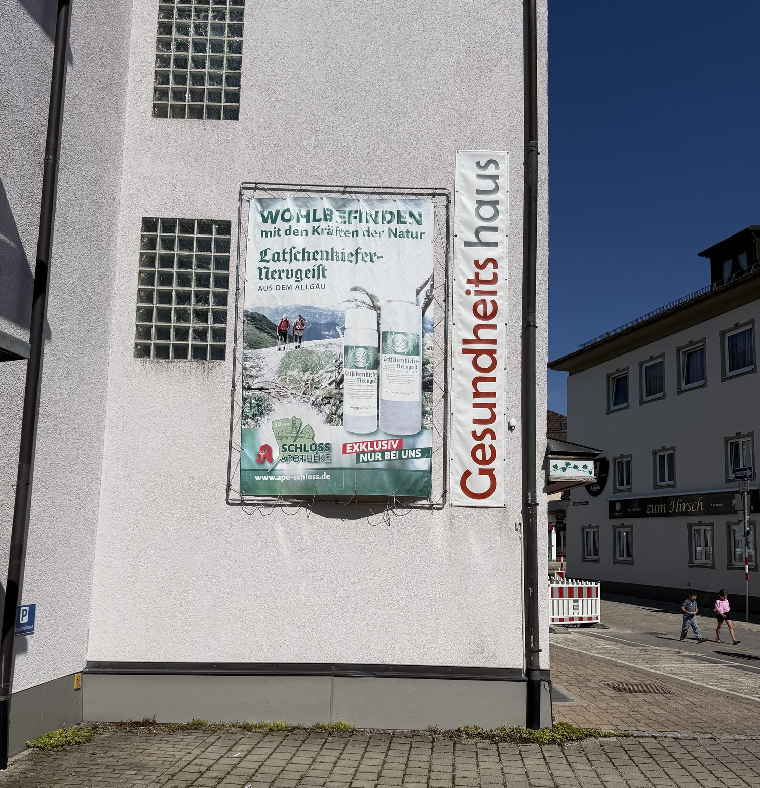 Altes, vergilbtes Werbebanner der Schloss-Apotheke im Rahmen an der Hauswand.